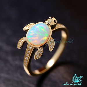 Op de afbeelding: Gouden ring met een schildpadontwerp met een witte opaal en heldere zirkonia-accenten.