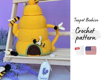 May include: A handmade yellow crochet teapot shaped like a beehive, adorned with crocheted bees. The teapot has a brown entrance and a green base. The text "Teapot Beehive Crochet pattern" is visible.