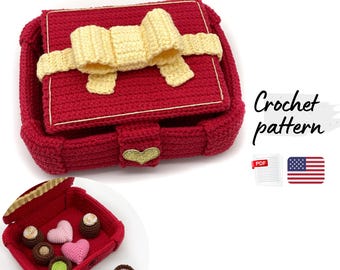 May include: A red crocheted box with a cream-colored bow on the lid and a gold heart-shaped clasp. The box opens to reveal various crocheted chocolates and heart shapes. The text Crochet pattern is visible next to a PDF icon and a US flag.