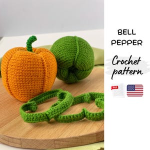 May include: Crocheted orange pumpkin and green bell pepper with green stems. Two green crocheted rings are in the foreground. The text "BELL PEPPER Crochet pattern" is on the right side of the image.