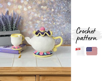 May include: A crocheted teapot and teacup set in white, yellow, pink, and purple. The teapot has a rounded body, a curved handle, and a decorative lid. The teacup sits on a matching coaster. The text "Crochet pattern" is visible.