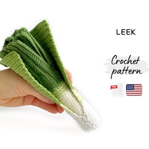Puede incluir: Un puerro tejido a mano en tonos verdes y blancos, sostenido en una mano. La imagen muestra el texto "LEEK" y "Crochet pattern". También hay un icono PDF y la bandera estadounidense. Fondo blanco.