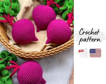 May include: A basket filled with crocheted beets, featuring vibrant magenta bodies and green leafy tops. The beets are arranged on a beige cloth, with additional green foliage around the basket. The image includes the text "Crochet pattern".