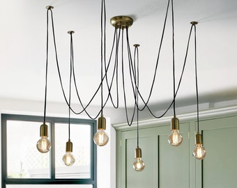 May include: A modern, multi-light pendant fixture with black cords and gold-toned metal accents. The fixture features six exposed bulbs, creating a warm and inviting ambiance.