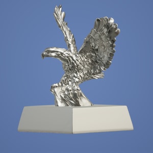 May include: A silver eagle statue with wings spread, perched on a rock, mounted on a square base.