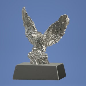 May include: A silver eagle statue with its wings spread wide, perched on a black base. The eagle is a popular symbol of freedom and strength.