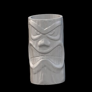 Op de afbeelding: Witte keramische tiki-mok met een gegraveerd boos gezicht. De mok heeft een brede opening en een cilindrische vorm.
