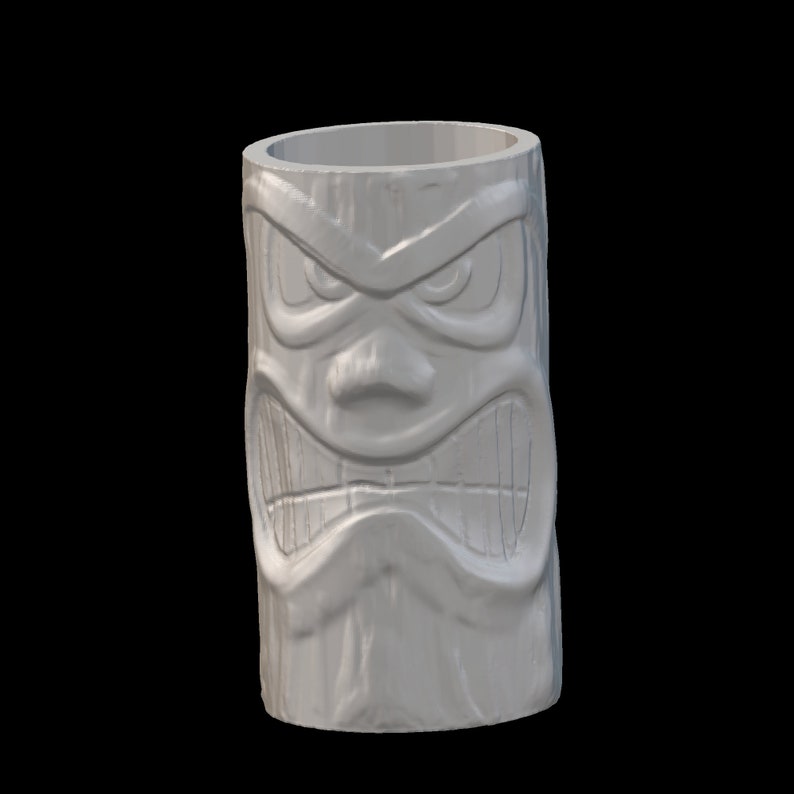 Op de afbeelding: Witte keramische tiki-mok met een gegraveerd boos gezicht. De mok heeft een brede opening en een cilindrische vorm.