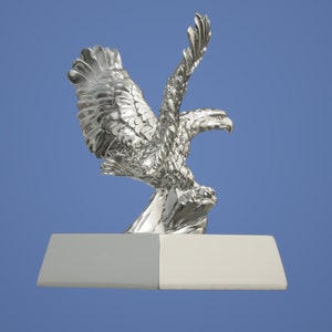May include: A silver eagle statue with outstretched wings, perched on a rock, mounted on a silver base.