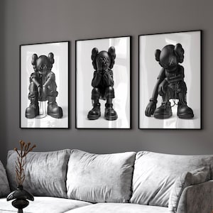 May include: Three black and white framed prints of a cartoon character with a black and white design. The character is sitting with its head down and hands covering its face. The character is wearing a black and white outfit.