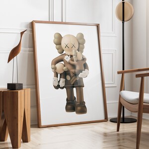 May include: A framed print of a brown and white cartoon character holding a smaller brown and white cartoon character. The larger character has an X on its eyes and is wearing a brown and white outfit. The print is on a white background and is framed in a brown frame.