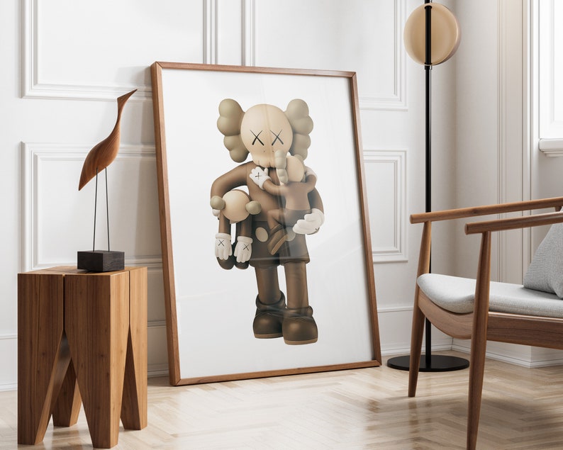 May include: A framed print of a brown and white cartoon character holding a smaller brown and white cartoon character. The larger character has an X on its eyes and is wearing a brown and white outfit. The print is on a white background and is framed in a brown frame.
