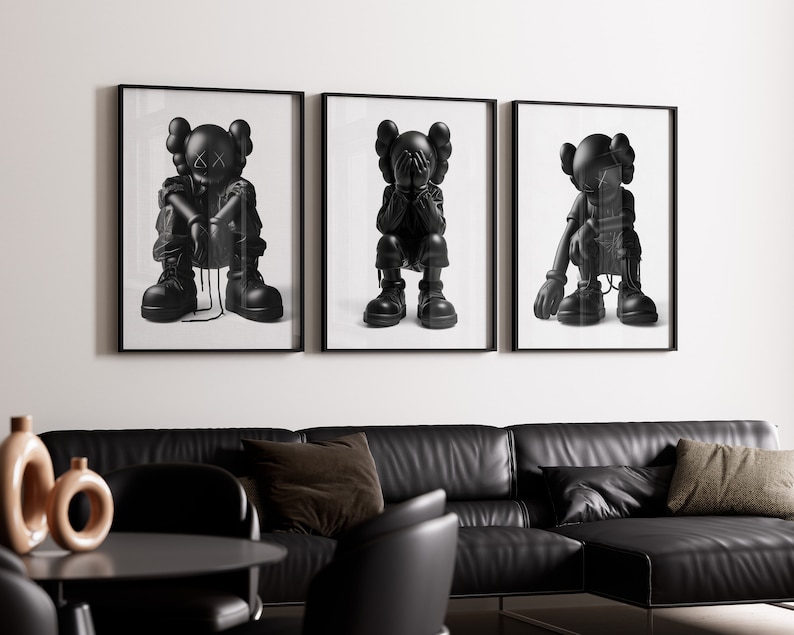Puede incluir: Tres impresiones enmarcadas en blanco y negro de un personaje de dibujos animados con diferentes poses. El personaje lleva un atuendo negro y tiene una cara en blanco y negro. Las impresiones est&aacute;n colgadas en una pared blanca.