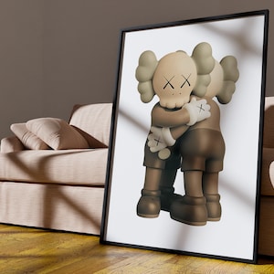 May include: A framed print of a brown and beige cartoon character with an X for eyes hugging another similar character. The background is white.