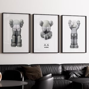 Puede incluir: Tres impresiones enmarcadas en negro de figuras de dibujos animados grises y blancas con el texto "XX KAWs" en la impresión del medio.