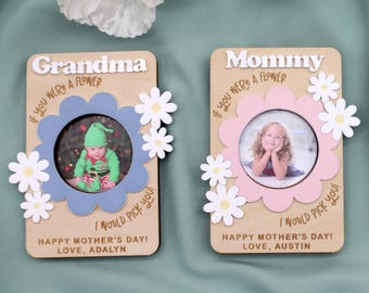 May include: Two wooden photo frames with flower-shaped cutouts. One frame says "Grandma" and has a blue flower, the other says "Mommy" with a pink flower. Both have photos inside and the text "If you were a flower, I would pick you!" and "Happy Mother's Day!"