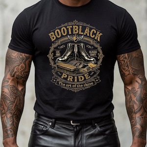 May include: A black short-sleeve t-shirt featuring a graphic print with the text BOOTBLACK PRIDE, EST. 1891, CLASSIC CRAFT, and The art of the shine. The design includes illustrations of leather boots, a shoe brush, and polish tins.