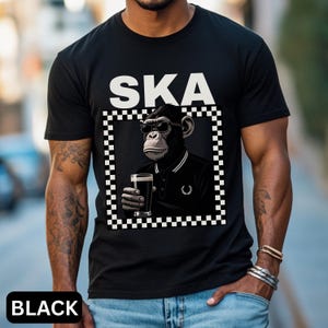 May include: Black t-shirt with the word "SKA" in white block letters. The shirt features a graphic of a chimpanzee wearing sunglasses and a black polo shirt, holding a glass of dark beer, framed by a black and white checkered border. The word "BLACK" is at the bottom.