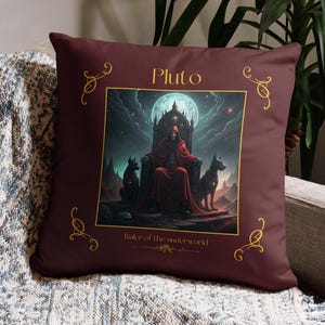 May include: A maroon cushion featuring an illustration of Pluto, the ruler of the underworld, seated on a throne with two black dogs. The cushion has gold decorative accents and text that reads "Pluto" and "Ruler of the underworld."