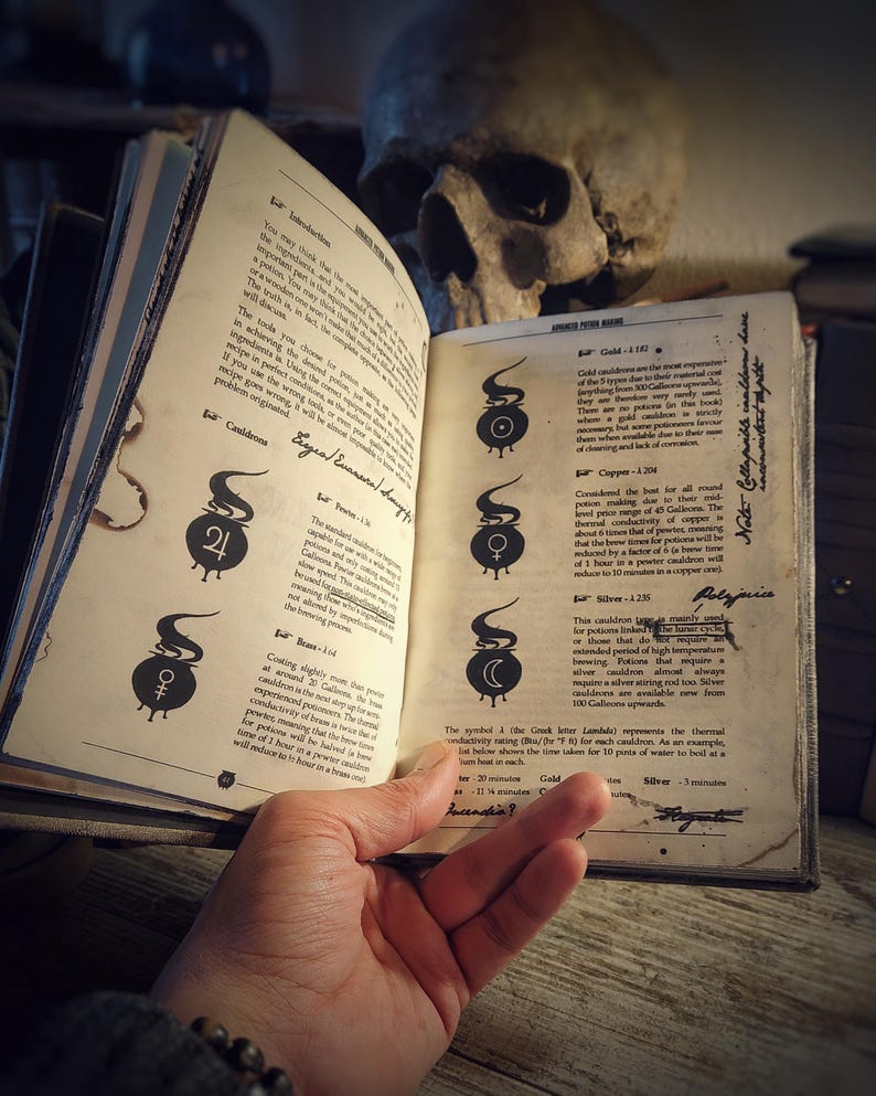 Op de afbeelding: Een open boek met een schedel erop. Het boek is getiteld "Advanced Potion Making" en heeft een sectie over ketels. De tekst beschrijft de verschillende soorten ketels en hun eigenschappen, waaronder hun kosten, warmtegeleiding en kooktijd. De ketels zijn ge&iuml;llustreerd met symbolen.
