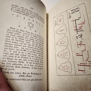 K&ouml;nnte beinhalten: Offenes Buch mit deutschem Text und Illustrationen. Die linke Seite zeigt Textabschnitte mit Symbolen, w&auml;hrend die rechte Seite Zeichnungen von Glocken und Symbolen zeigt. Der Text ist in schwarzer Tinte, und die Illustrationen sind in roter Tinte.