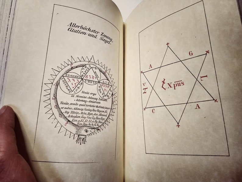 K&ouml;nnte beinhalten: Offene Buchseiten mit Vintage-Illustrationen und Text. Eine Seite zeigt ein kreisf&ouml;rmiges Diagramm mit Text und Symbolen, die andere eine sternf&ouml;rmige Figur mit Buchstaben und Symbolen. Der Text enth&auml;lt deutsche und lateinische S&auml;tze.