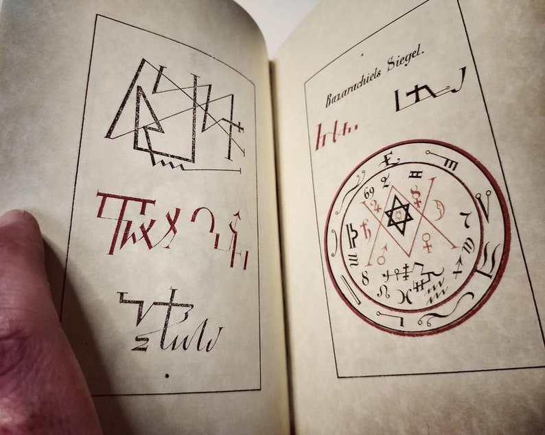 K&ouml;nnte beinhalten: Offene Buchseiten mit okkulten Symbolen und Text. Die linke Seite zeigt geometrische Formen und stilisierte Schrift in schwarzer und roter Tinte. Die rechte Seite zeigt ein kreisf&ouml;rmiges Design mit einem sechszackigen Stern, umgeben von Symbolen und dem Text "Bazanichiels Siegel."