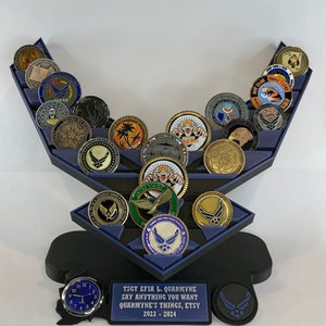 May include: A blue and black Air Force themed coin display stand with a clock and a plaque that reads "TSGT EFIA L. QUARMYNE SAY ANYTHING YOU WANT QUARMYNE'S THINGS, ETSY 2023 - 2024".