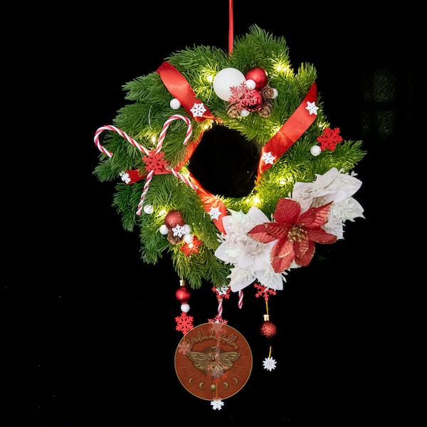 Couronne de porte Noël Authentique sur fausses branches de sapin avec poinsettias blanc et rouge, cannes à sucres et flocons en bois.