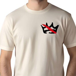 Peut inclure: T-shirt cr&egrave;me avec un motif de couronne noire barr&eacute;e d'un trait rouge. Le motif est situ&eacute; sur la poitrine gauche. Le t-shirt a des manches courtes et un col rond.
