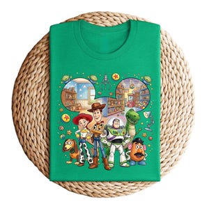 Pode incluir: Uma camiseta verde com um gr&aacute;fico colorido dos personagens de Toy Story. O design apresenta Woody, Buzz Lightyear, Jessie, Rex, Sr. Batata e Slinky Dog, com um fundo detalhado de uma loja de brinquedos.