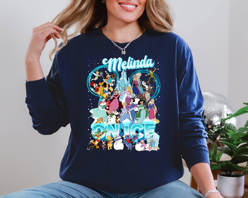 Puede incluir: Una sudadera azul marino con un gr&aacute;fico de personajes de Disney de Frozen y otras pel&iacute;culas de Disney. El texto "Melinda" y "&Eacute;rase una vez" est&aacute; impreso en la sudadera.