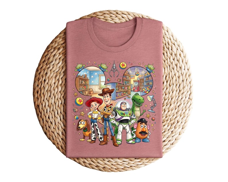 Pode incluir: Camiseta cor de malva com um gr&aacute;fico colorido de personagens de Toy Story. O design inclui Woody, Buzz Lightyear, Jessie, Rex, Sr. Batata e Slinky Dog, com elementos de fundo detalhados.