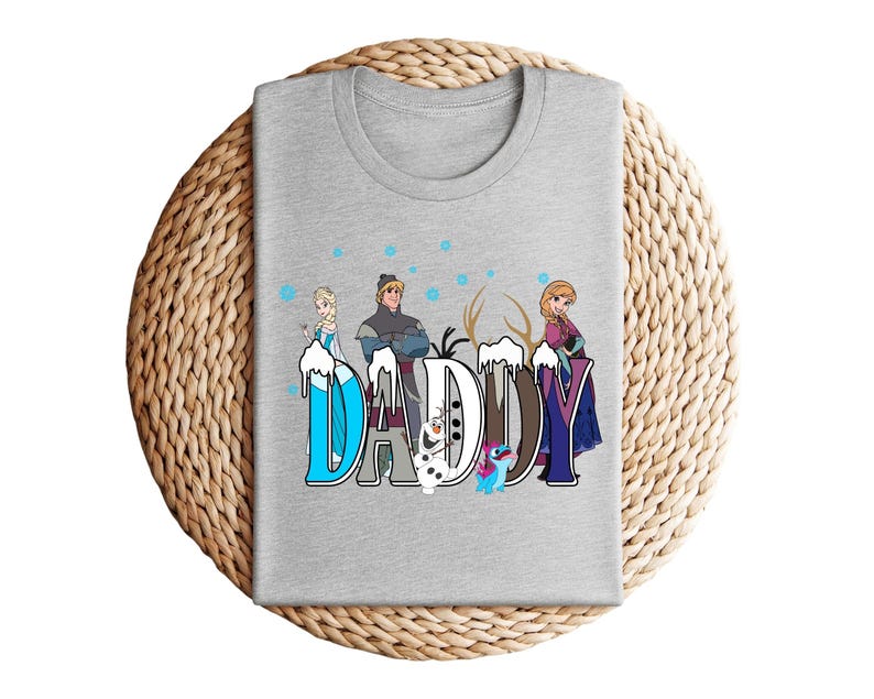 May include: A heather gray t-shirt featuring the word "DADDY" in a stylized font with characters from the movie Frozen. The design includes Elsa, Kristoff, Anna, Olaf, and Sven, with a snowy effect.