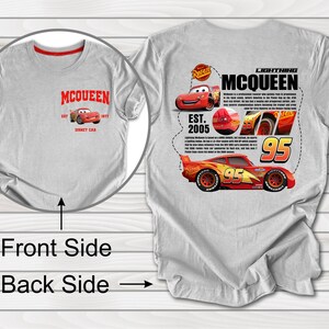 Puede incluir: Camiseta gris con un dise&ntilde;o de Rayo McQueen rojo y blanco en la espalda. La parte delantera de la camiseta tiene un logotipo de McQueen rojo y blanco con el texto "EST. 2005" y "HONEY CAR".