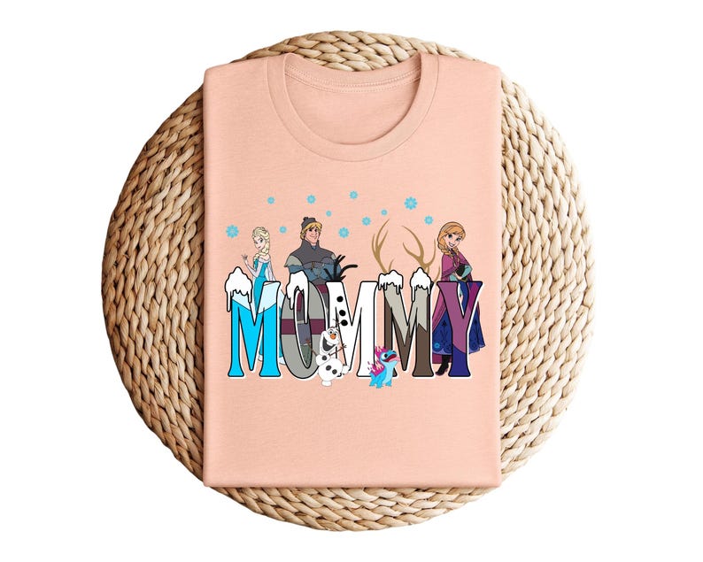 May include: A peach-colored t-shirt featuring the word "MOMMY" in a stylized font with characters from the movie Frozen. The design includes Elsa, Kristoff, Anna, Olaf, and Stitch, with snowflakes and antlers.