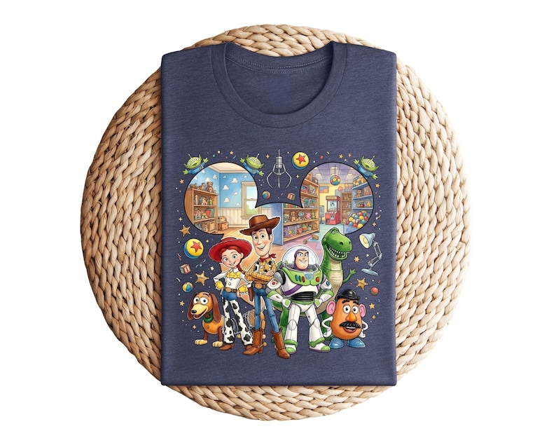Pode incluir: Camiseta azul marinho com um gr&aacute;fico colorido dos personagens de Toy Story, incluindo Woody, Buzz Lightyear e Rex. O design inclui uma ilustra&ccedil;&atilde;o l&uacute;dica de uma loja de brinquedos e v&aacute;rias estrelas e figuras alien&iacute;genas. A camiseta &eacute; exibida em uma superf&iacute;cie tecida.
