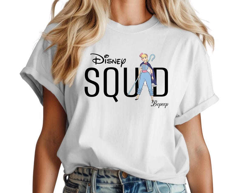 Puede incluir: Camiseta blanca con la frase "Disney Squad" y una ilustraci&oacute;n de dibujos animados de Bo Peep. El dise&ntilde;o incluye el nombre de Bo Peep. Las mangas de la camiseta est&aacute;n enrolladas.