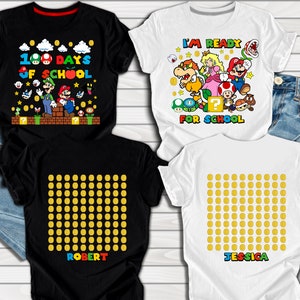 Puede incluir: Dos camisetas blancas y negras con tem&aacute;tica de Mario Bros. Una camiseta dice "100 d&iacute;as de escuela" con los personajes de Mario y Luigi. La otra camiseta tiene una cuadr&iacute;cula de monedas de oro y el nombre "Robert". Dos camisetas blancas con tem&aacute;tica de Mario Bros. Una camiseta dice "Estoy listo para la escuela" con Mario, Luigi, Peach, Bowser y otros personajes. La otra camiseta tiene una cuadr&iacute;cula de monedas de oro y el nombre "Jessica".