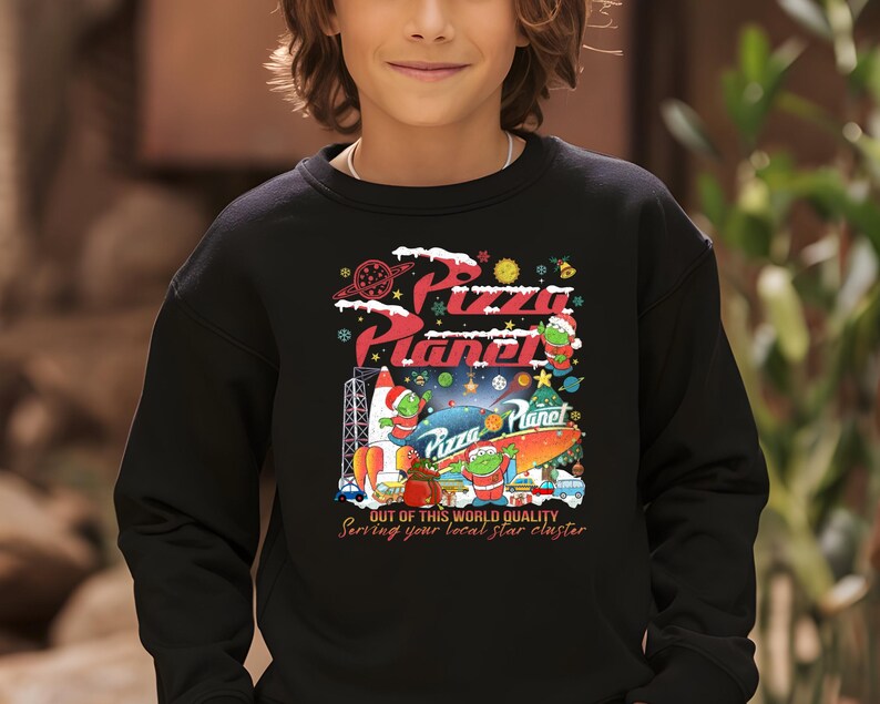 May include: Black sweatshirt with a Christmas-themed Pizza Planet design. It features a rocket, a Christmas tree, and three alien characters. The text reads "Pizza Planet" and "Out of this world quality. Serving your local star cluster."