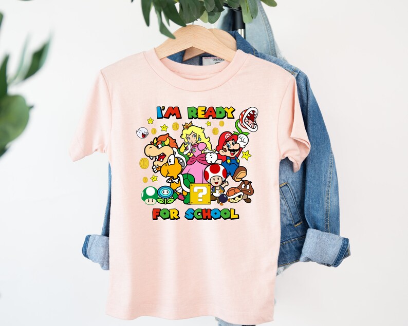 Puede incluir: Camiseta rosa con un gr&aacute;fico de Mario y sus amigos del videojuego Super Mario Bros. El texto "I'm Ready for School" est&aacute; impreso en la camiseta.