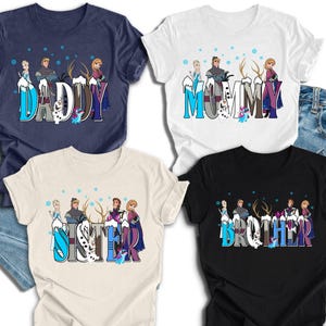 May include: Four t-shirts with the words "DADDY", "MOMMY", "SISTER", and "BROTHER" in a stylized font. Each shirt features a cartoon design with characters and snowflakes. The shirts are navy, white, beige, and black.