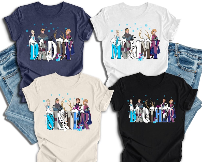 May include: Four t-shirts with the words "DADDY", "MOMMY", "SISTER", and "BROTHER" in a stylized font. Each shirt features a cartoon design with characters and snowflakes. The shirts are navy, white, beige, and black.