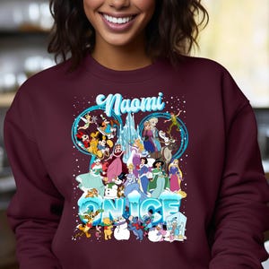 Puede incluir: Sudadera color burdeos con un gr&aacute;fico de personajes de Disney de Frozen y otras pel&iacute;culas de Disney. El texto "Naomi" y "On Ice" est&aacute; impreso en la sudadera.