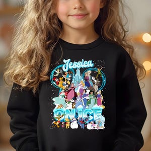 Puede incluir: Sudadera negra con un gr&aacute;fico colorido de personajes de Disney, incluyendo Mickey Mouse, Minnie Mouse y princesas, con el texto "Jessica Nice" en la parte delantera.