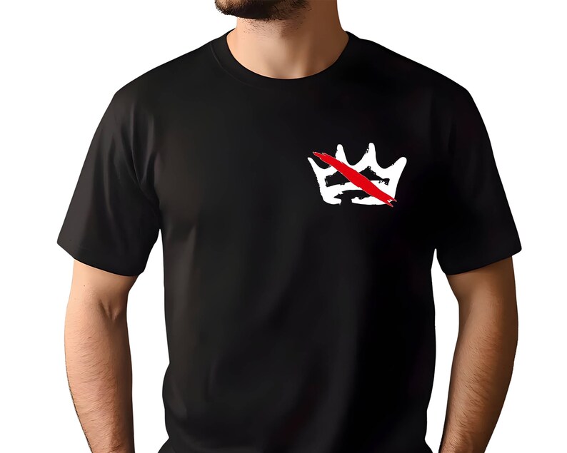 Peut inclure: T-shirt noir avec un motif de couronne blanche barr&eacute;e d'une barre rouge. Le motif est situ&eacute; sur la poitrine gauche. Le t-shirt a des manches courtes et un col rond.