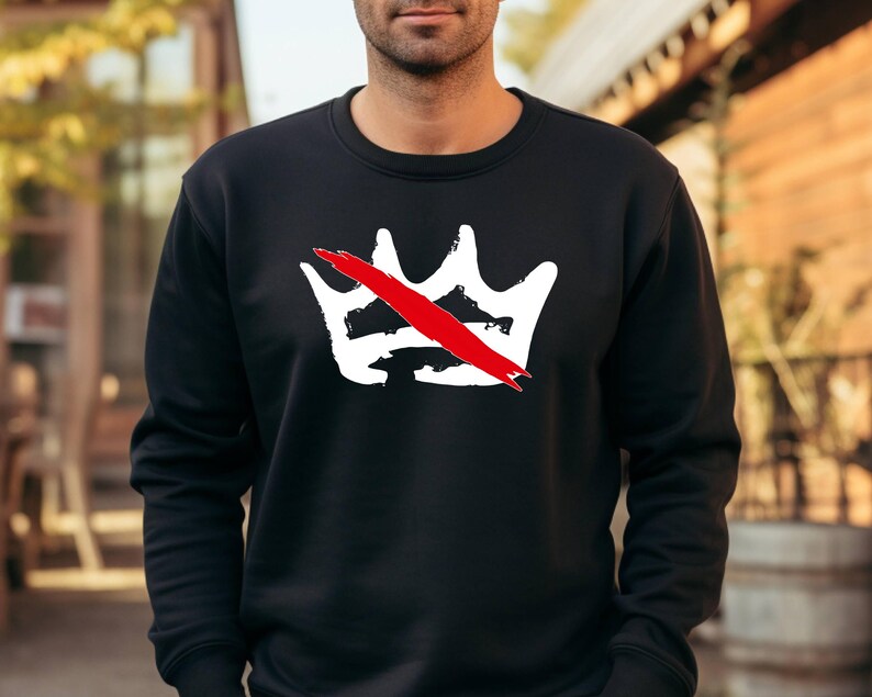 Peut inclure: Sweat-shirt noir &agrave; col rond avec un motif de couronne blanche barr&eacute;e d'une barre rouge. Le motif est centr&eacute; sur la poitrine. Le sweat-shirt est en mati&egrave;re souple.