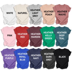 Puede incluir: Una colecci&oacute;n de 15 camisetas de varios colores, incluyendo blanco, rosa, rojo, granate, verde, azul verdoso, morado, azul, azul marino, gris oscuro y negro. Cada camiseta tiene un color o tono de jaspeado diferente, con el nombre del color impreso en blanco en la parte delantera.