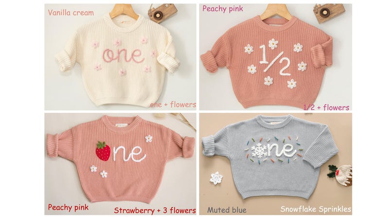 May include: Four different knit sweaters for babies, each with a different design and color. The sweaters are white with pink embroidery, peach with white embroidery, peach with red embroidery, and blue with white embroidery. The sweaters all say "one" on them.