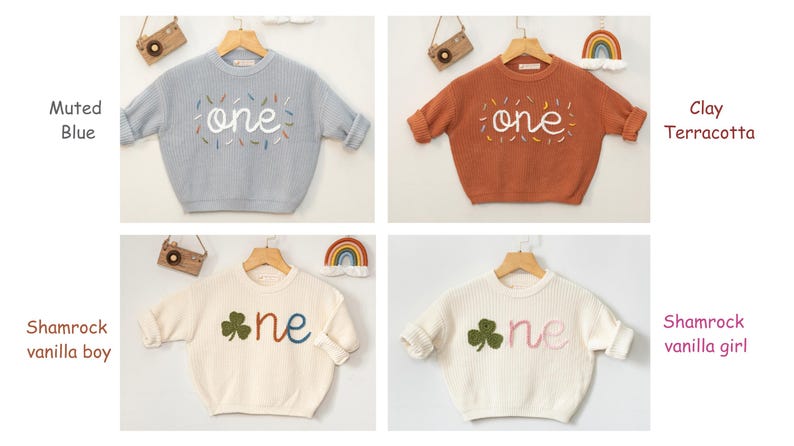 May include: Four different colored knitted baby sweaters with the word "one" embroidered on the front. The sweaters are in muted blue, clay terracotta, and two shades of white.